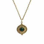Collier doré avec pendentif soleil et pierre verte type malachite sur fond blanc