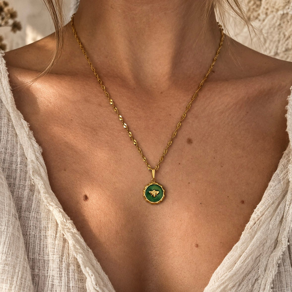 Collier pendentif abeille vert et doré porté par une femme