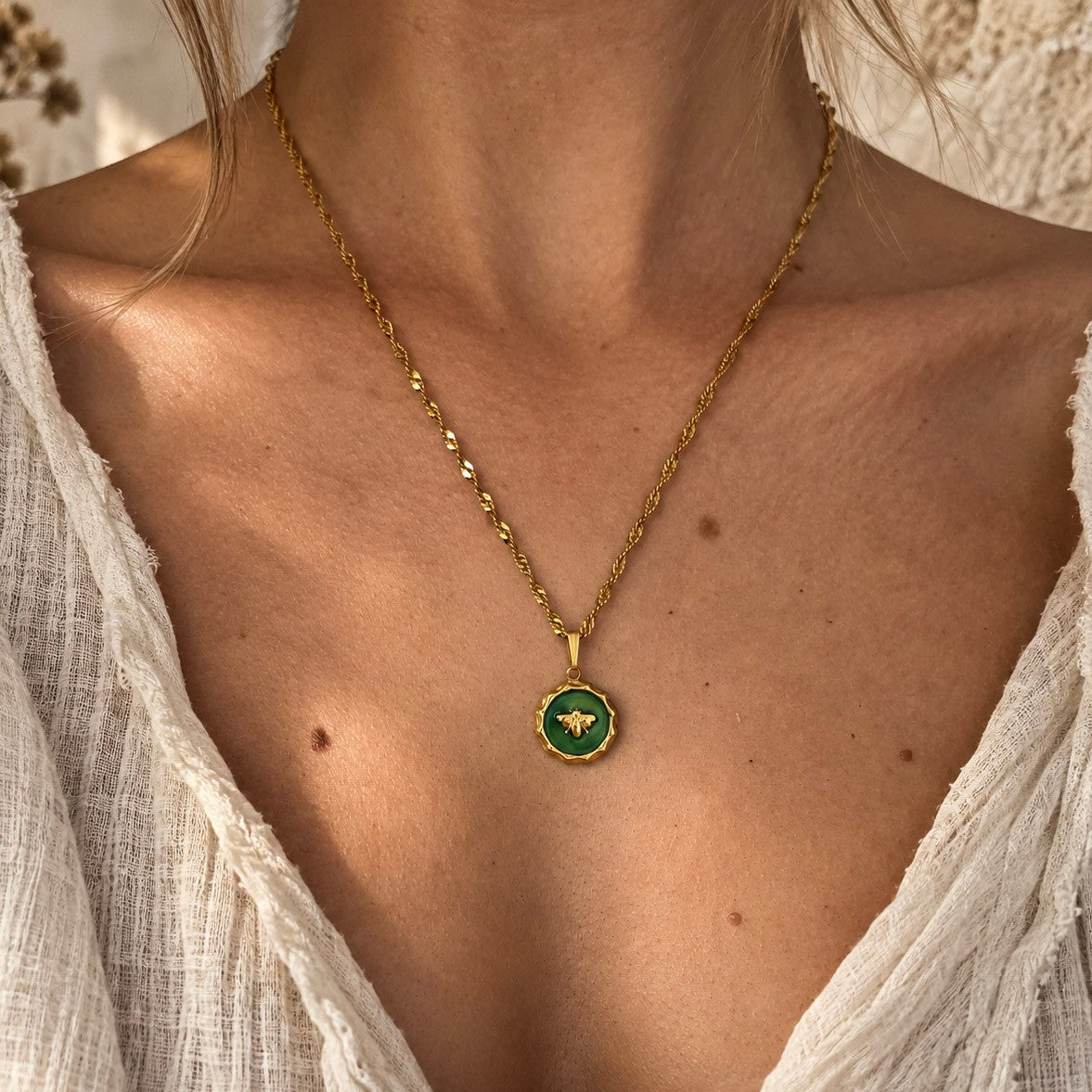 Collier pendentif abeille vert et doré porté par une femme