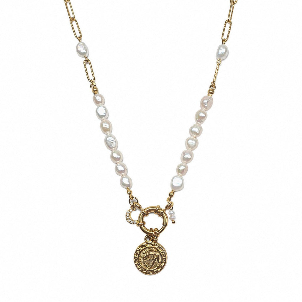 Collier femme en perles d’eau douce avec chaîne dorée, pendentif oeil et breloque lune sur fond blanc