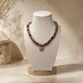 Collier en perles de rhodonite avec pendentif oeil doré présenté sur buste