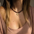 Collier en rhodonite naturelle porté au cou avec médaille dorée