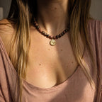 Collier en rhodonite naturelle porté au cou avec médaille dorée