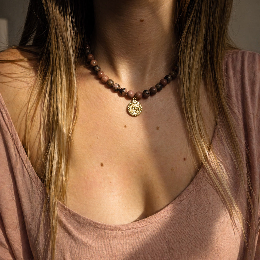 Collier en rhodonite naturelle porté au cou avec médaille dorée