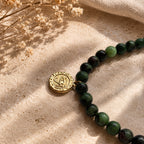 Détail du collier en rubis zoïsite naturel et de sa médaille œil dorée