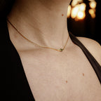 Collier ras-du-cou pour femme en acier inoxydable doré, avec tube doré et perle centrale verte subtile — design minimaliste élégant signé Clyvia Bijoux.