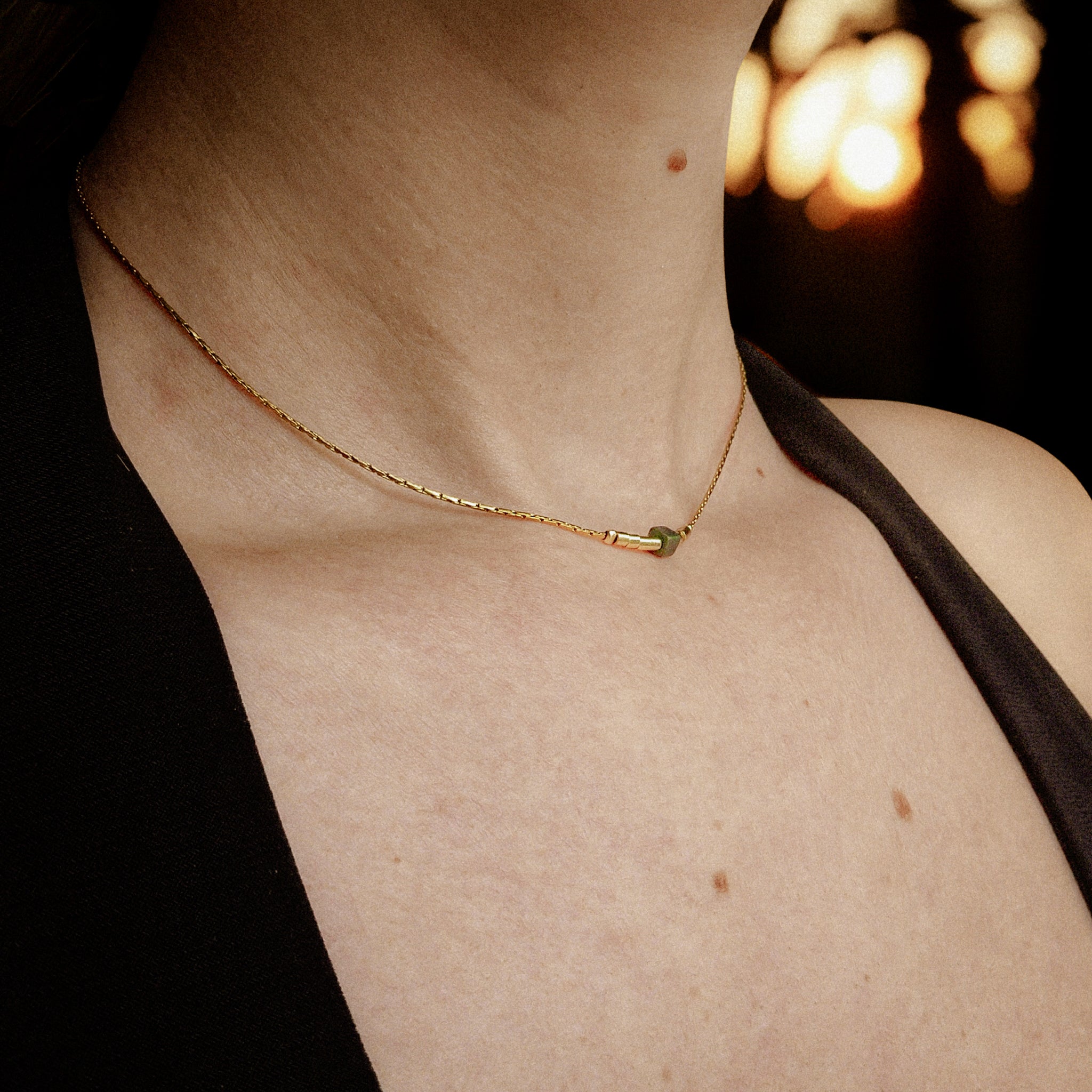 Collier ras-du-cou pour femme en acier inoxydable doré, avec tube doré et perle centrale verte subtile — design minimaliste élégant signé Clyvia Bijoux.