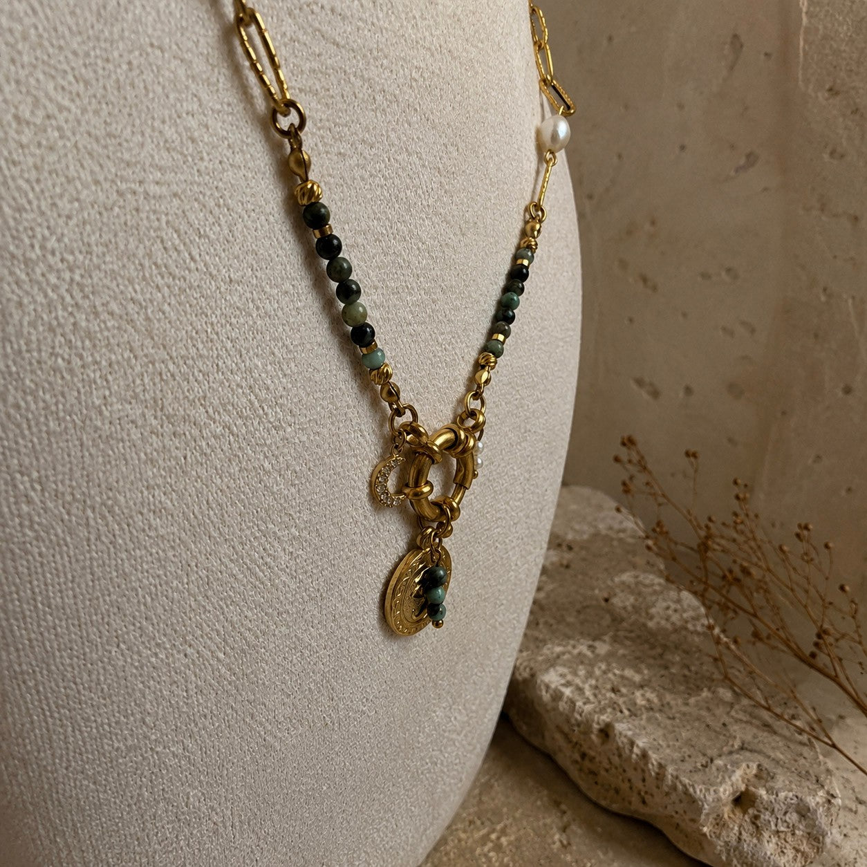 Détail d’un collier doré avec perles de turquoise africaine, fermoir rond, pendentif oeil et breloque lune