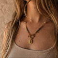 Collier porté en turquoise africaine avec chaîne dorée, perles blanches, pendentif oeil et breloque lune
