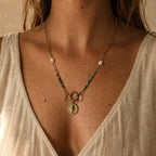 Collier porté en turquoise africaine avec chaîne dorée, perles blanches, pendentif oeil et breloque lune