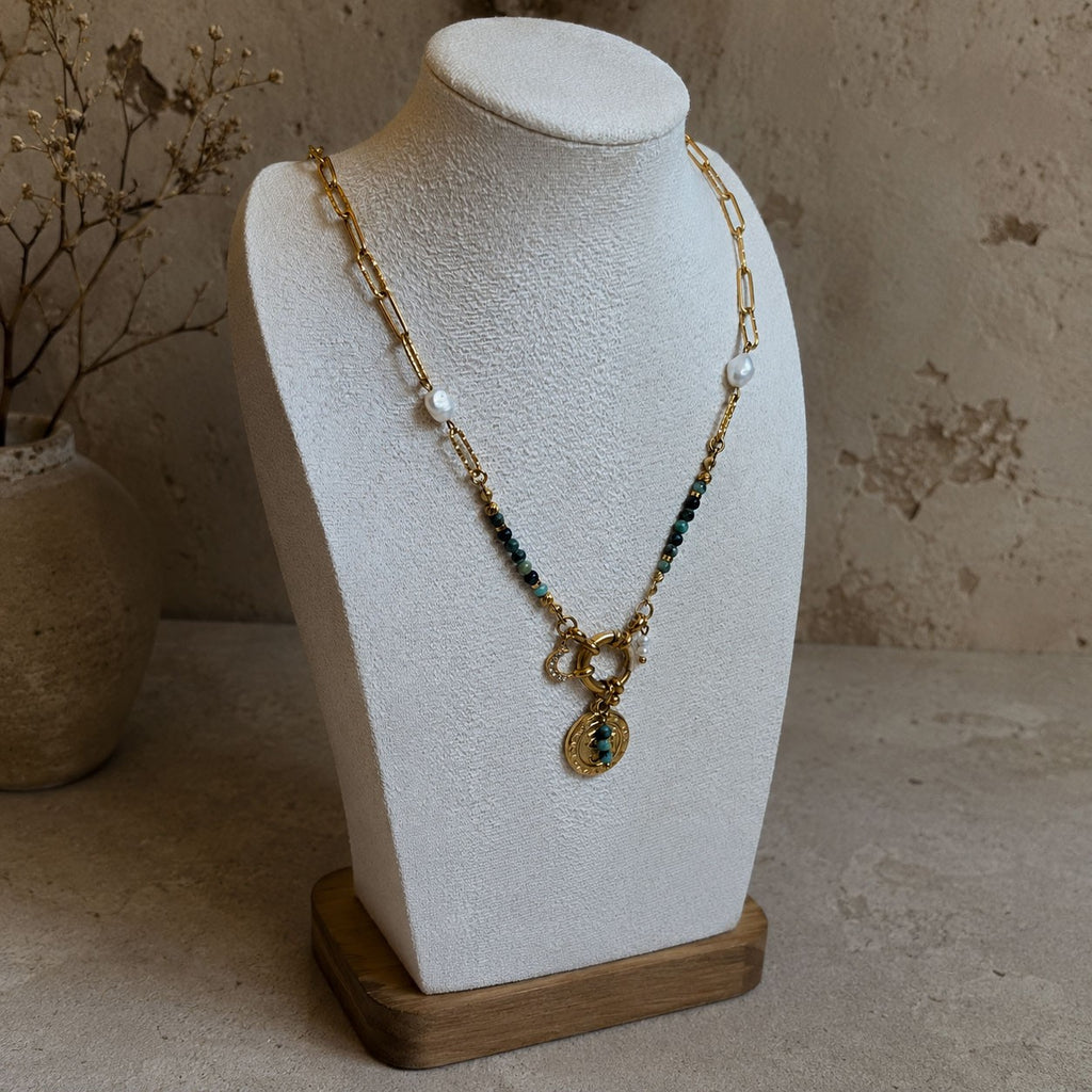 Collier en turquoise africaine et chaîne dorée présenté sur buste avec pendentif oeil et perles blanches