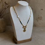 Collier en turquoise africaine et chaîne dorée présenté sur buste avec pendentif oeil et perles blanches