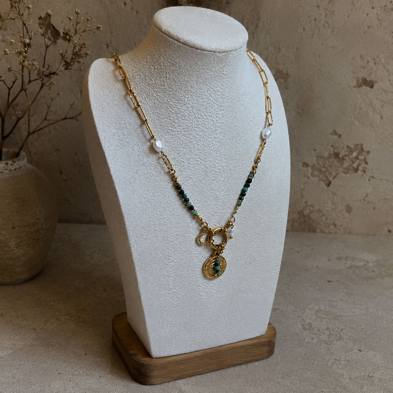 Collier en turquoise africaine et chaîne dorée présenté sur buste avec pendentif oeil et perles blanches