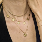 Femme portant plusieurs colliers et bracelets fins dorés en acier inoxydable — superposition élégante de chaînes martelées et tubes lisses, style contemporain et lumineux signé Clyvia Bijoux.