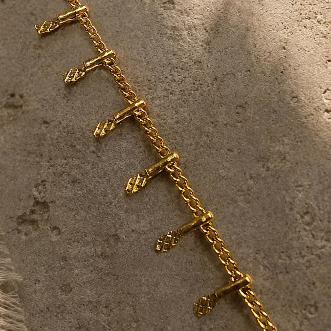Détail des petites pampilles texturées et de la chaîne dorée du bracelet Orelk
